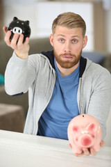 man holding two different sized piggybanks