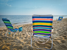 Vibrant Striped Beach Chairs On The Beach.  Three Empty Chairs Waiting For Vacationers To Arrive.