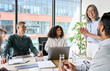 © insta_photos - Senior older female executive ceo and happy multicultural business people discuss corporate project at boardroom table. Smiling diverse corporate team working together in modern meeting room office.