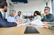 Diverse professional executive business team people discuss project sitting at meeting table in board room. Multiethnic company managers brainstorm financial plan working together in boardroom.