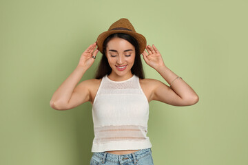 Wall Mural - Beautiful young woman wearing straw hat on olive  background. Stylish headdress