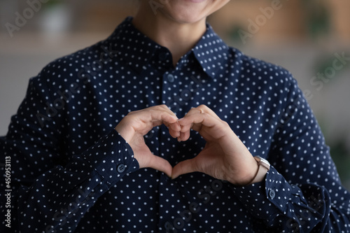 Crop close up of Indian woman show love heart hand gesture feel supportive grateful and thankful. Biracial female make sign demonstrate support and care, volunteer give help. Charity concept.