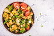 Rustic vegetarian potato salad with green onions, parsley and mint in a plate with tomato halves in a plate, top view, copy space