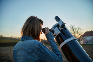 Wall Mural - Woman looking at night sky with amateur astronomical telescope.