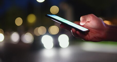 Male hand using mobile phone in the night city messaging online