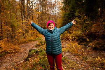 Wall Mural - Happy woman hiker is walking in the beautiful autumn forest