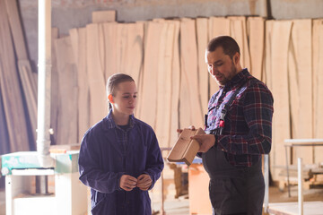 Young apprentice learning to work at carpentry shop