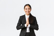 Hopeful glad asian businesswoman in black suit bowing politely and say namaste, greeting clients and smiling friendly. Thankful female manager thanking for help, being grateful, appreciate help