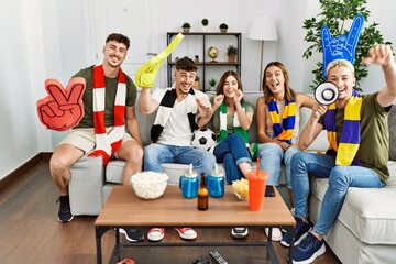 Canvas Print - Group of young friends watching and supporting soccer match at home.