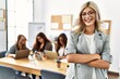 © Krakenimages.com - Young businesswoman smiling happy standing with arms crossed gesture while partners work at the office.