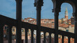 San Marco bell tower over traditional Venetian houses viewed between columns in Venice, Italy