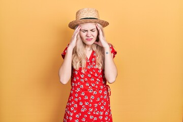 Poster - Beautiful caucasian woman with blond hair wearing summer hat with hand on head for pain in head because stress. suffering migraine.