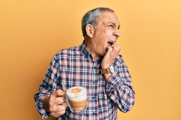 Poster - Handsome senior man with grey hair drinking a cup coffee looking stressed and nervous with hands on mouth biting nails. anxiety problem.