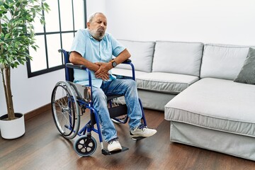 Wall Mural - Handsome senior man sitting on wheelchair at the living room with hand on stomach because nausea, painful disease feeling unwell. ache concept.