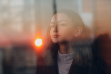 Beautiful young teenager girl portrait behind window glass.