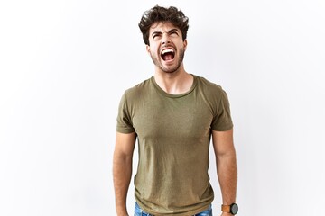 Sticker - Hispanic man standing over isolated white background angry and mad screaming frustrated and furious, shouting with anger. rage and aggressive concept.