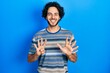 © Krakenimages.com - Handsome hispanic man wearing casual clothes over pink background showing and pointing up with fingers number nine while smiling confident and happy.