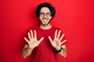 Canvas Print - Handsome hispanic man wearing casual t shirt and glasses showing and pointing up with fingers number ten while smiling confident and happy.