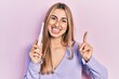 © Krakenimages.com - Beautiful hispanic woman holding electric toothbrush smiling happy pointing with hand and finger to the side