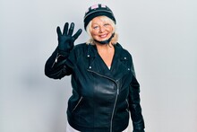 Middle Age Blonde Woman Holding Motorcycle Helmet Showing And Pointing Up With Fingers Number Four While Smiling Confident And Happy.