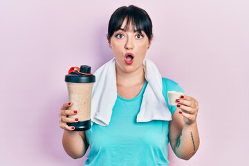 Sticker - Young hispanic woman wearing sportswear holding water bottle afraid and shocked with surprise and amazed expression, fear and excited face.