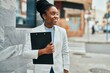 © Krakenimages.com - Young african american businesswoman smiling happy holding clipboard at the city.