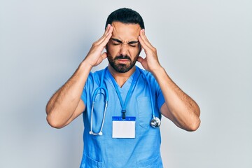 Canvas Print - Handsome hispanic man with beard wearing doctor uniform suffering from headache desperate and stressed because pain and migraine. hands on head.