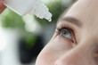 Woman dripping into her eyes with antibacterial drops closeup