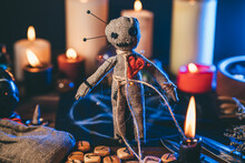 Voodoo Doll Studded With Needles In Magical Table With Candles And Occult Objects. Magic And Dark Spooky Ritual. Retribution Or Revenge Through Witchcraft Concept.