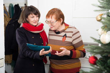 Positive mature woman answering questions of female interviewer at her home for New Year holiday..