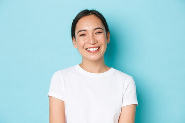 close-up of cheerful carefree asian girl in white t-shirt smiling broadly. pleasant korean female lo