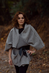 Poster - Curly Caucasian woman wearing a sweater and posing in the forest