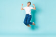 © Mix and Match Studio - Fashion, beauty and lifestyle concept. Cheerful triumphing, attractive asian girl jumping from happiness and joy, winning competition, celebrating victory over light blue background