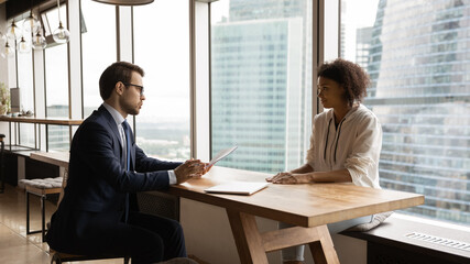 Sticker - Young female African ethnicity applicant sit in front of corporation executive HR manager, pass job interview in modern skyscraper office. Hiring process, apply for company position, staffing concept