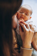 © Ananass - Loving mom carying of her newborn baby at home. Close up portrait of happy sleeping infant child on hands. Mother hugging her little 1 months old daughter.