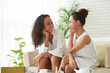 © DragonImages - Joyful beautiful women sitting on sofa in living room and discussing news and sharing secrets