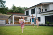© Halfpoint - Father with three daughters playing outdoors in the backyard, running.