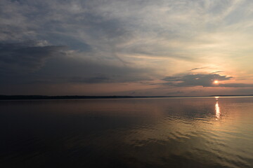 Wall Mural - Sunbeam from clouds at sunset over calm lake water
