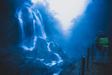 Poster - Tourist taking pictures in front of a waterfall.