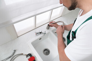 Canvas Print - Professional plumber fixing water tap in kitchen, above view