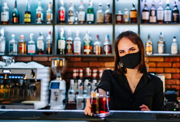 Portrait of young attractive woman bartender with mask Making Cocktail in bar