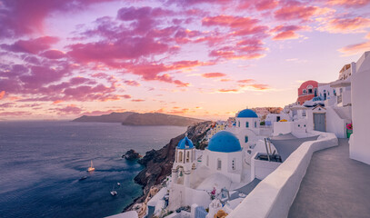 Beautiful panorama view of Santorini island in Greece at sunrise with dramatic sky. Stunning Oia cityscape, sunset colors sky with blue domes with white architecture. Amazing travel vacation landscape