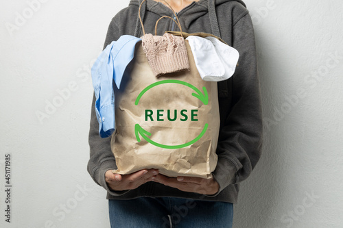 Woman holding paper bag with Reuse sign and full of apparel.Pack with reuse symbol.Clothes for donation or recycling