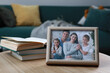 Framed family photo and books on wooden table indoors