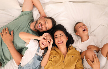 Wall Mural - Happy family with children having fun on bed, top view