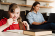 © Drobot Dean - Girl doing homework while her mother working with laptop