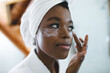 © Wavebreak Media - Smiling african american woman in bathroom applying face cream for skin care