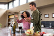 © Wavebreak Media - Happy diverse couple in kitchen preparing food together eating and smiling