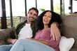 © Wavebreak Media - Portrait of happy diverse couple sitting on sofa in living room embracing and smiling