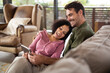 © Wavebreak Media - Happy diverse couple sitting on sofa in living room using tablet